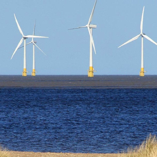 offshore wind turbines a few miles out from a sandy beach